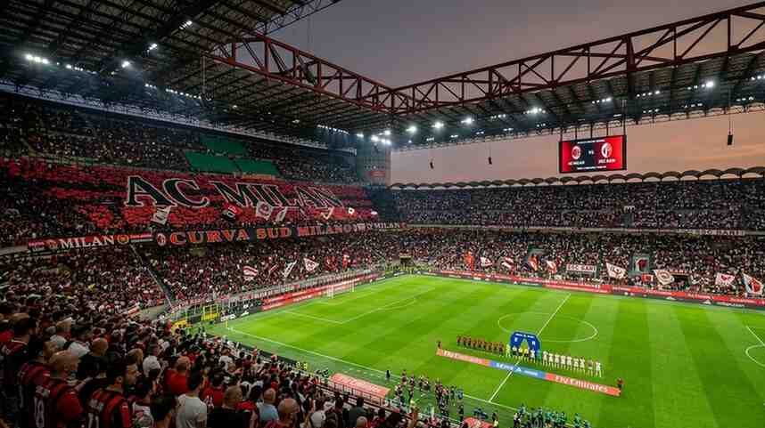 A professional 4K wide-angle view of the San Siro stadium filled with AC Milan and SSC Bari fans during a night match.